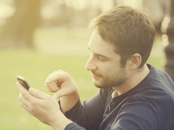 Photo d'une personne utilisant un telephone portable sur un banc.